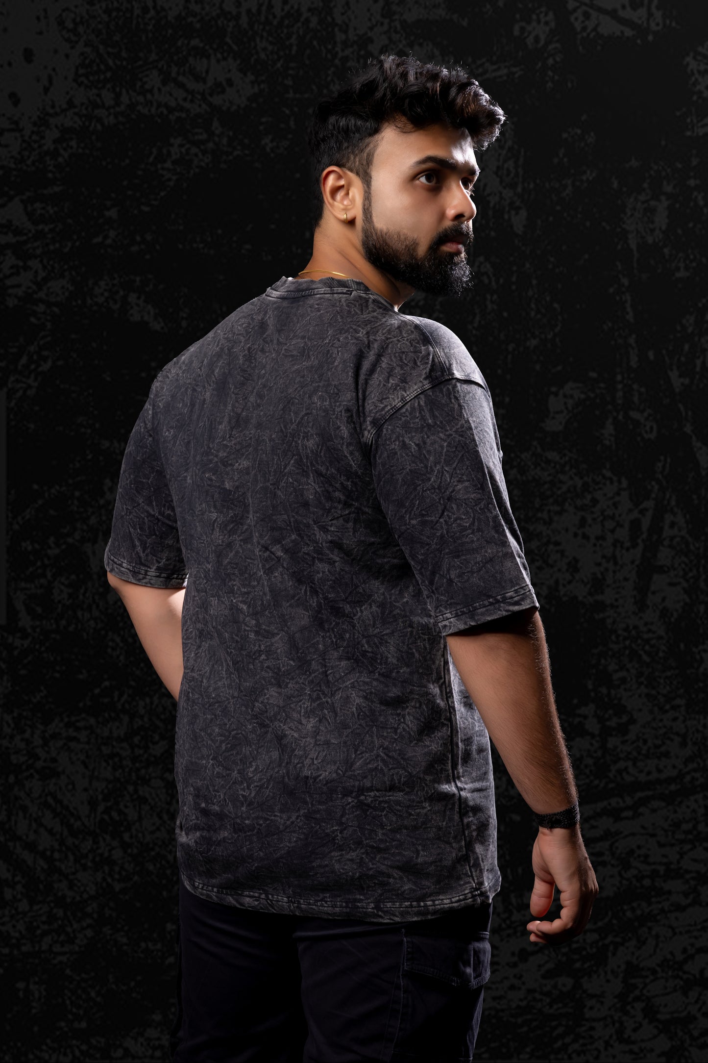 Man wearing a dark gray t-shirt against a black background