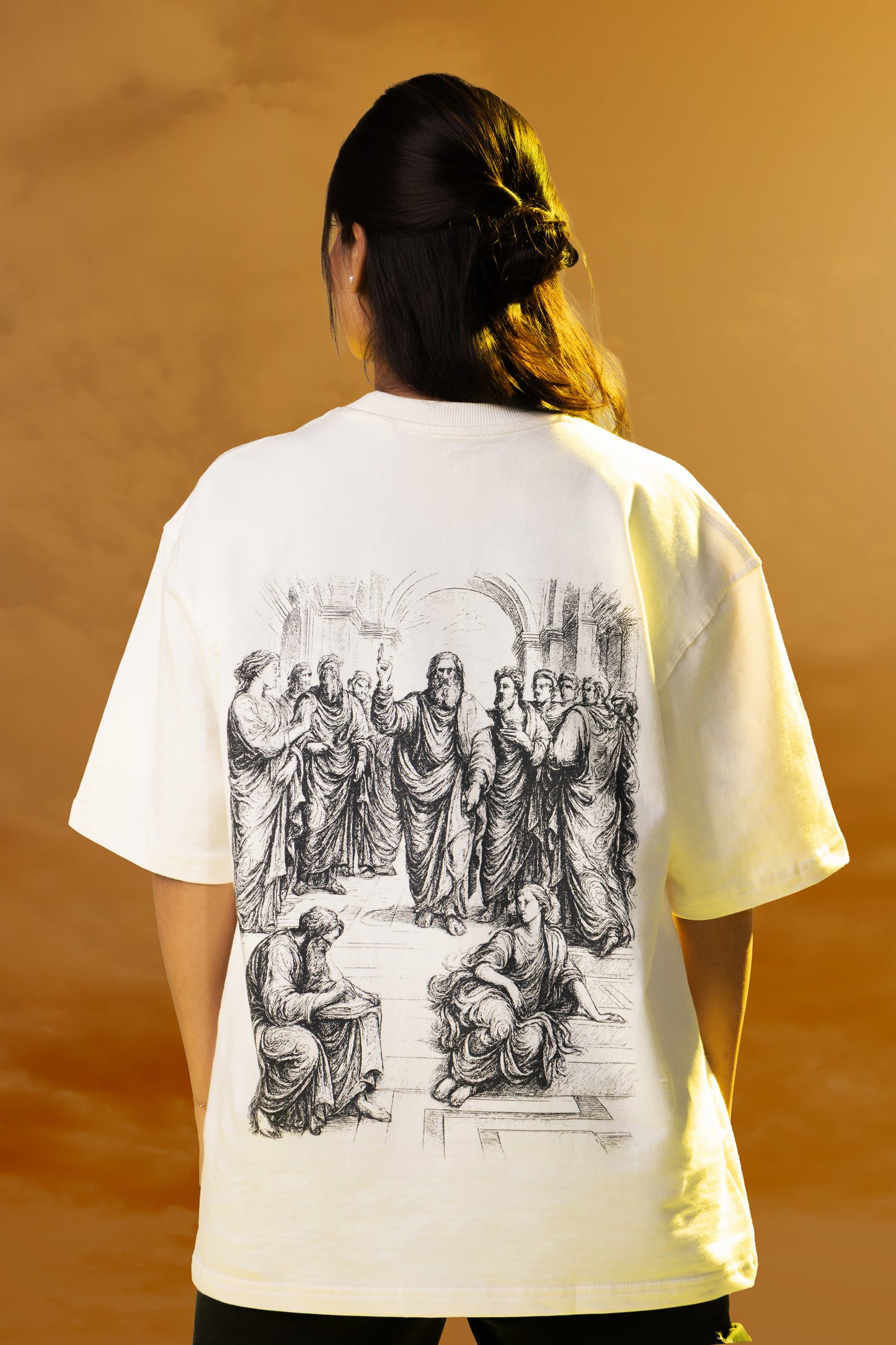 Person wearing a white t-shirt with black graphic design on the back against a warm-toned background