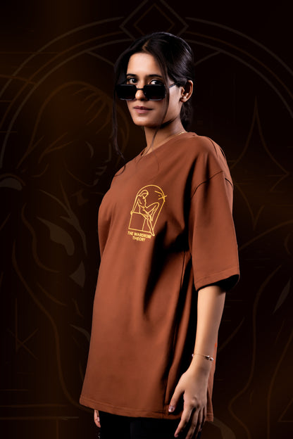 Woman wearing a brown t-shirt with a logo against a dark background